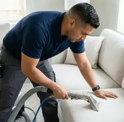 Professional upholstery cleaning technician using an extraction wand to deep-clean a fabric sofa, Bellevue, WA.